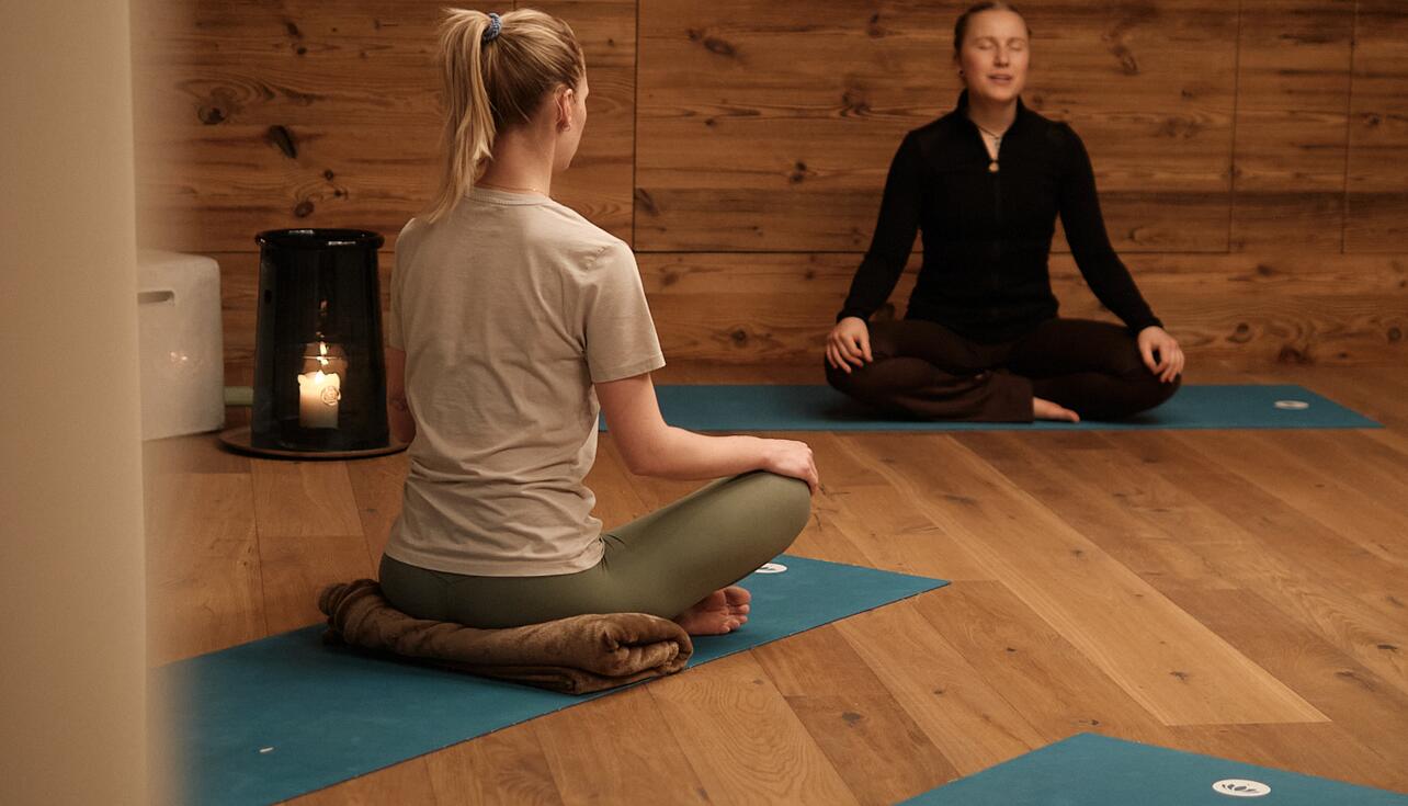 Zwei Frauen entspannen beim Yoga in einem Holzraum