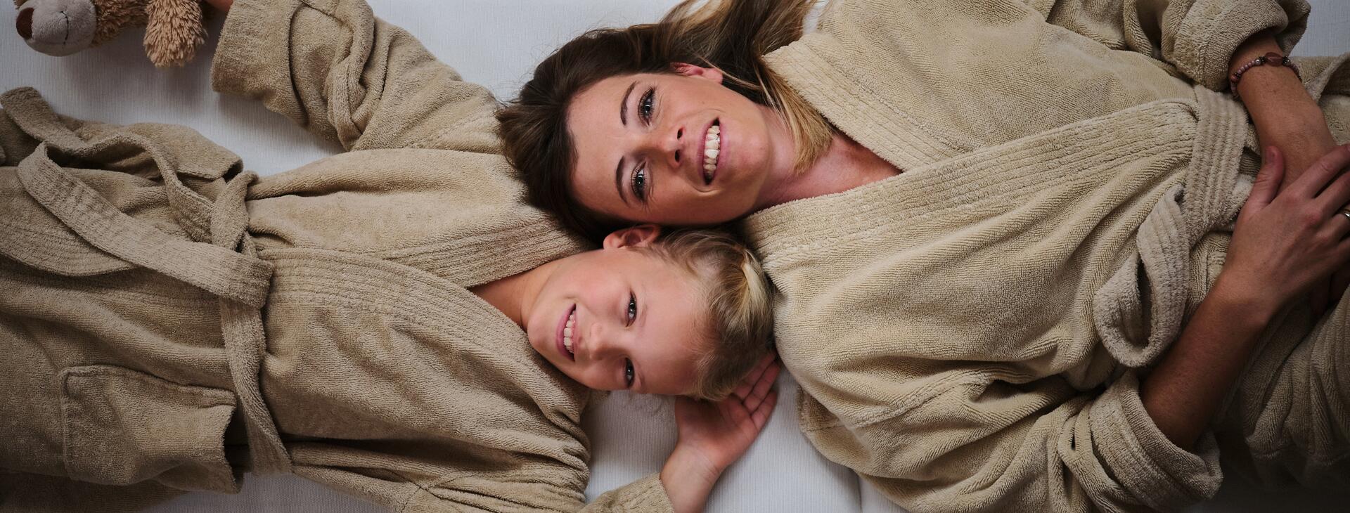 Tochter und Mutter im Bademantel im Familien-Spa