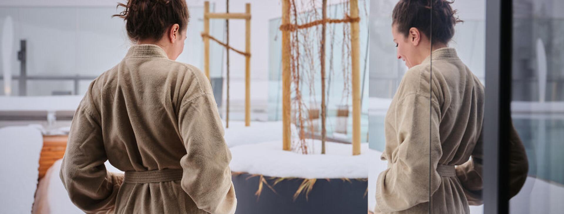 Woman in bathrobe by the snow-covered infinity pool.