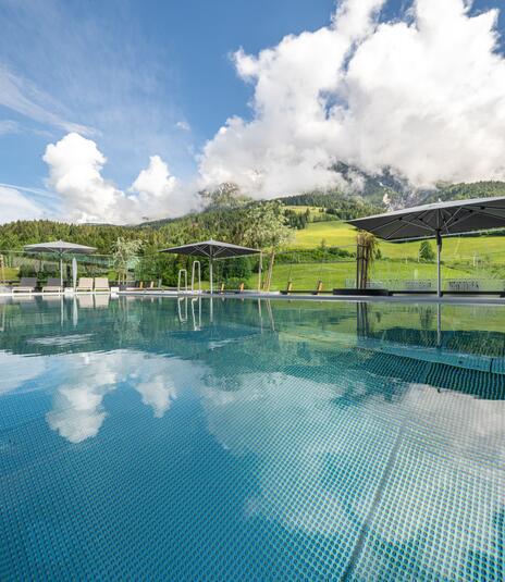 Au&szlig;enpool vor bew&ouml;lkter Berglandschaft