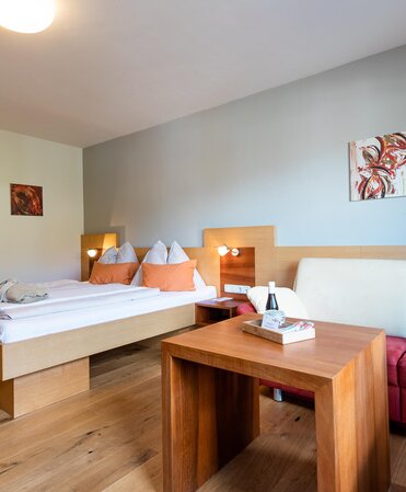 Zimmer mit moderner Couch und Doppelbett auf Holzboden