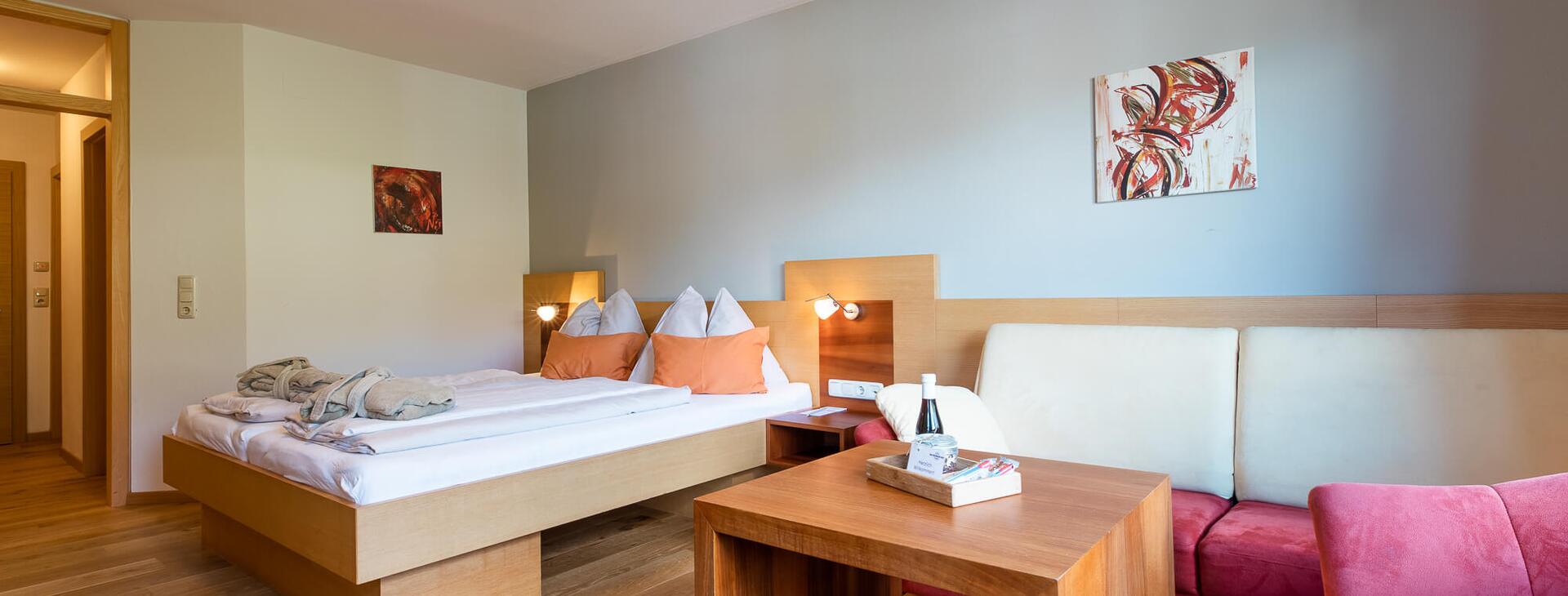 Zimmer mit moderner Couch und Doppelbett auf Holzboden