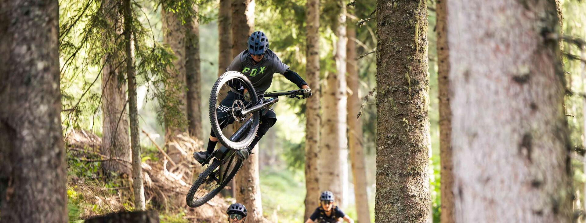 Personen fahren und springen auf Downhill Trail im Wald
